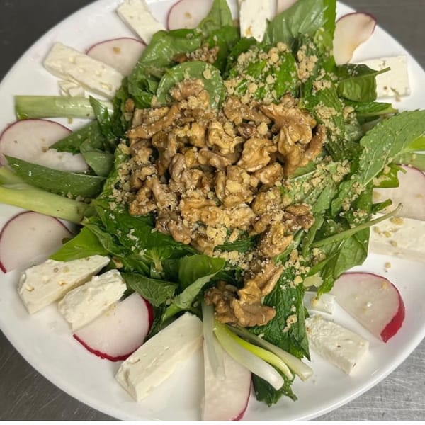 A Persian salad with fresh herbs, walnuts, radishes, green onions, and feta cheese.