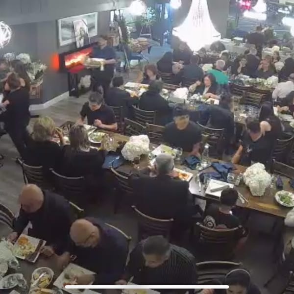 Diners enjoying meals at tables in a busy Persian restaurant with a server carrying a tray.