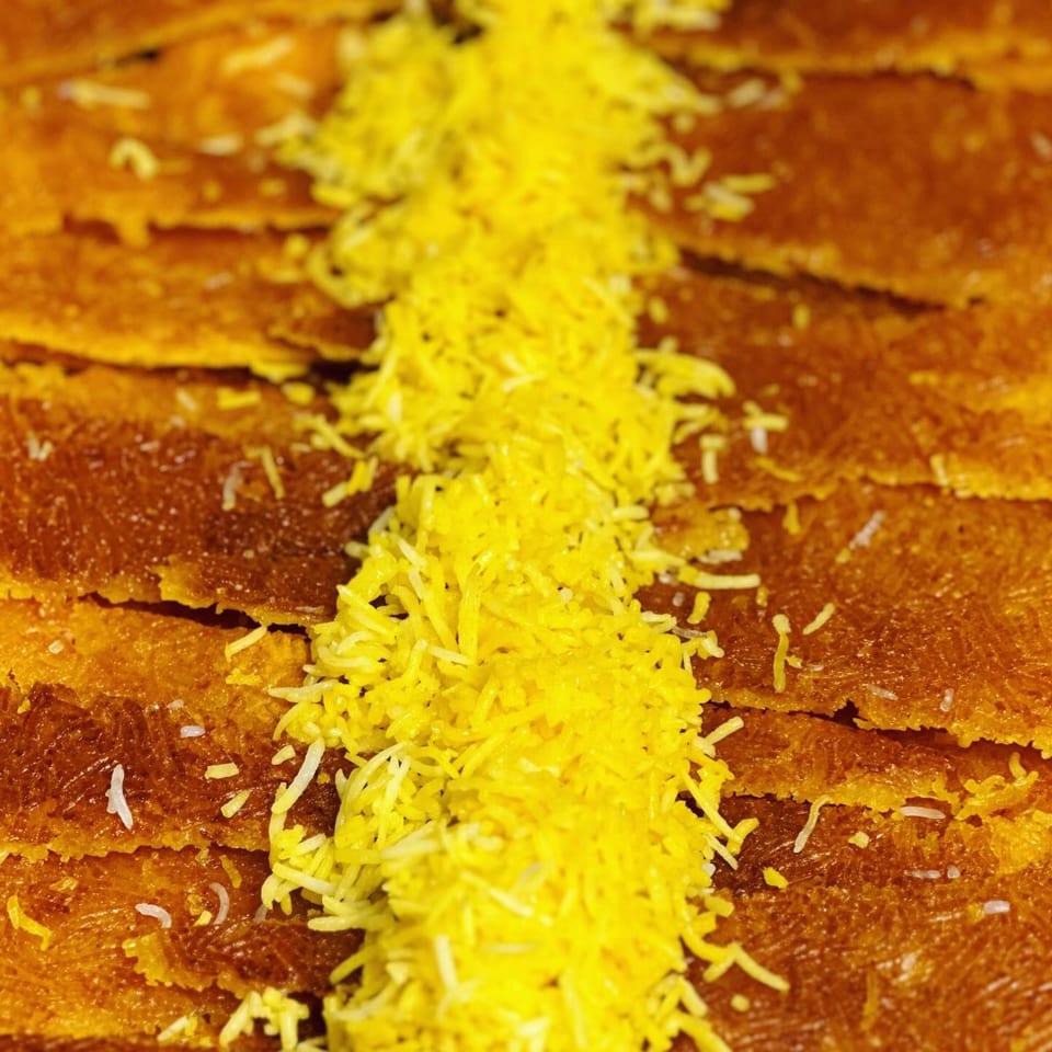 Close-up of golden Persian tahdig with a stripe of yellow saffron rice down the center.