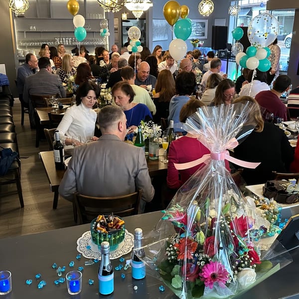 Guests seated at tables in Parisa Persian Grill, decorated with balloons and gifts for a celebration.